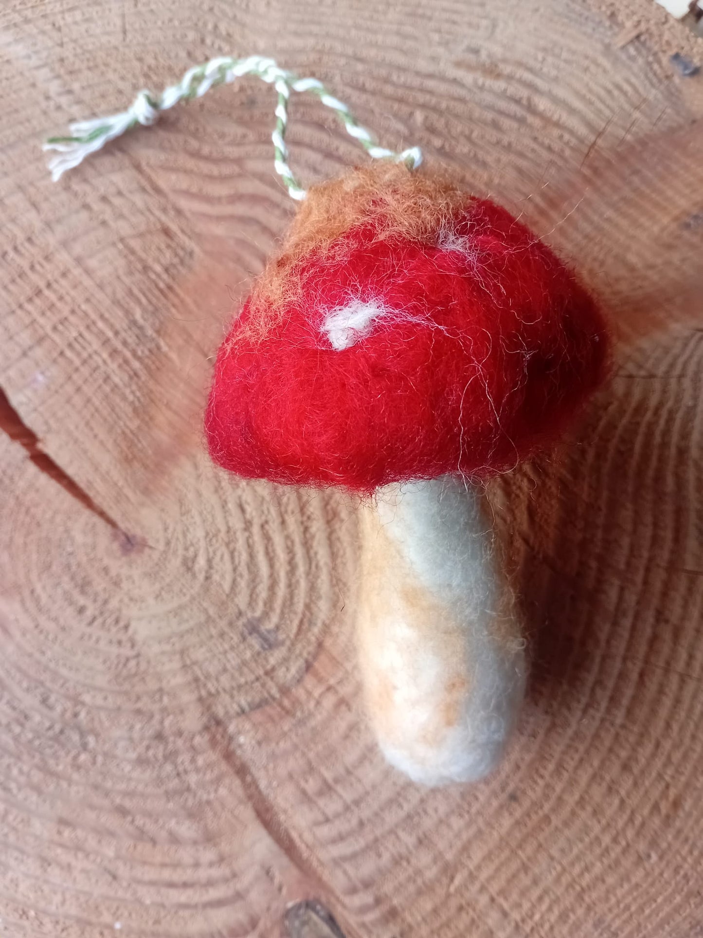 Fly agaric hand felted mushroom against a tree stump back ground