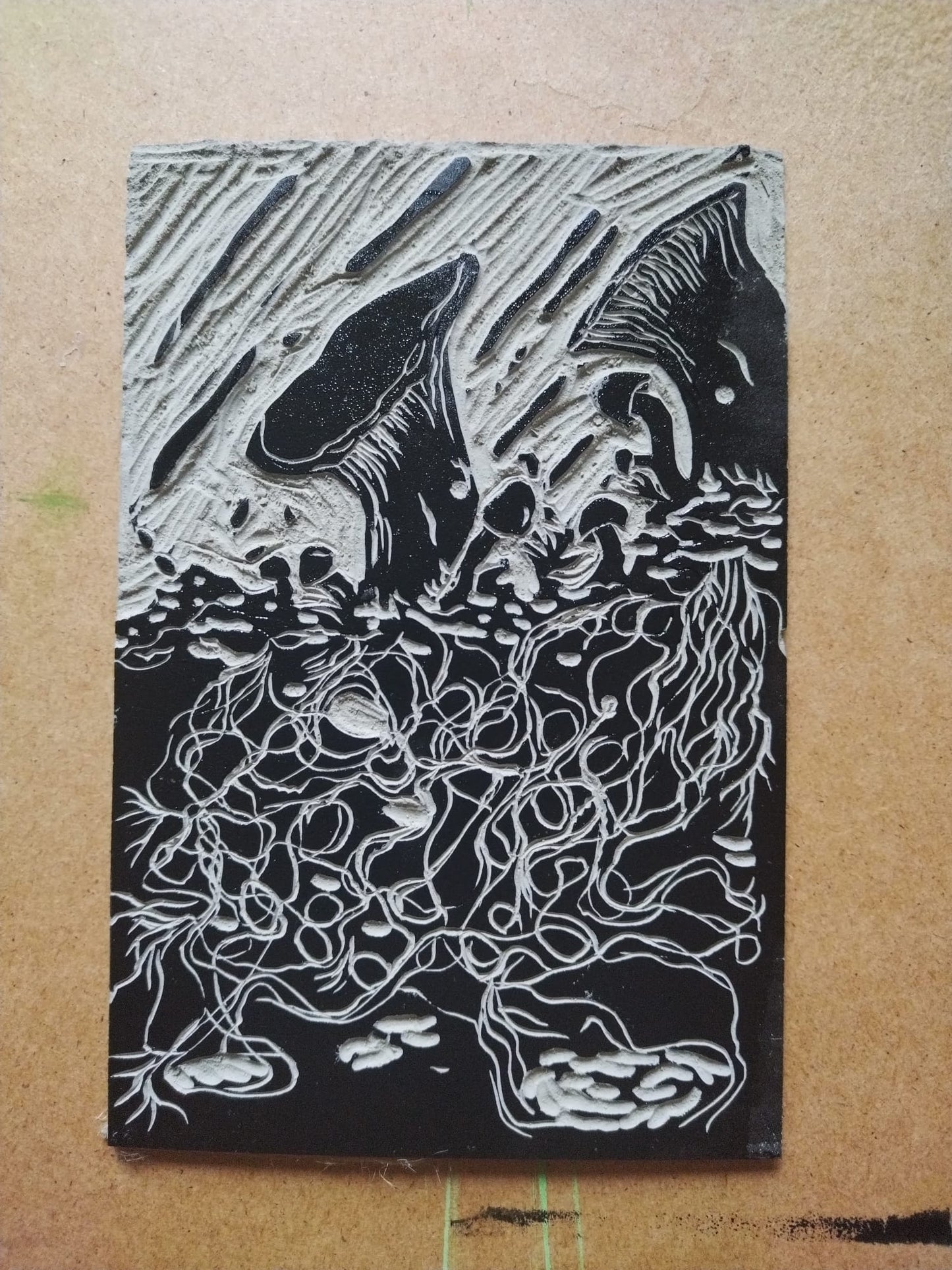 An image of the lino block used in the linocut print Wet Mycelials. This shows the block with printing ink on it, ready for Sophie to print.
