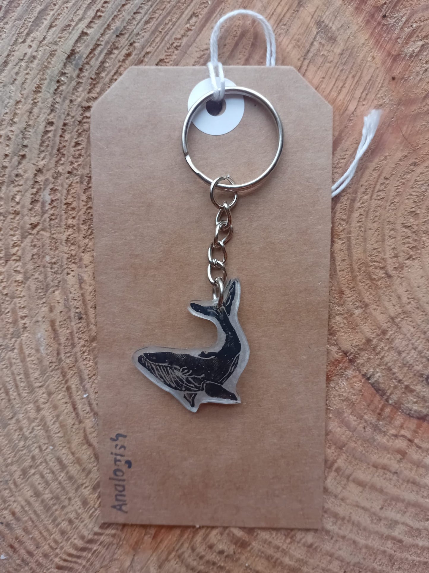 Keychain with whale design on a brown tag against a wooden background