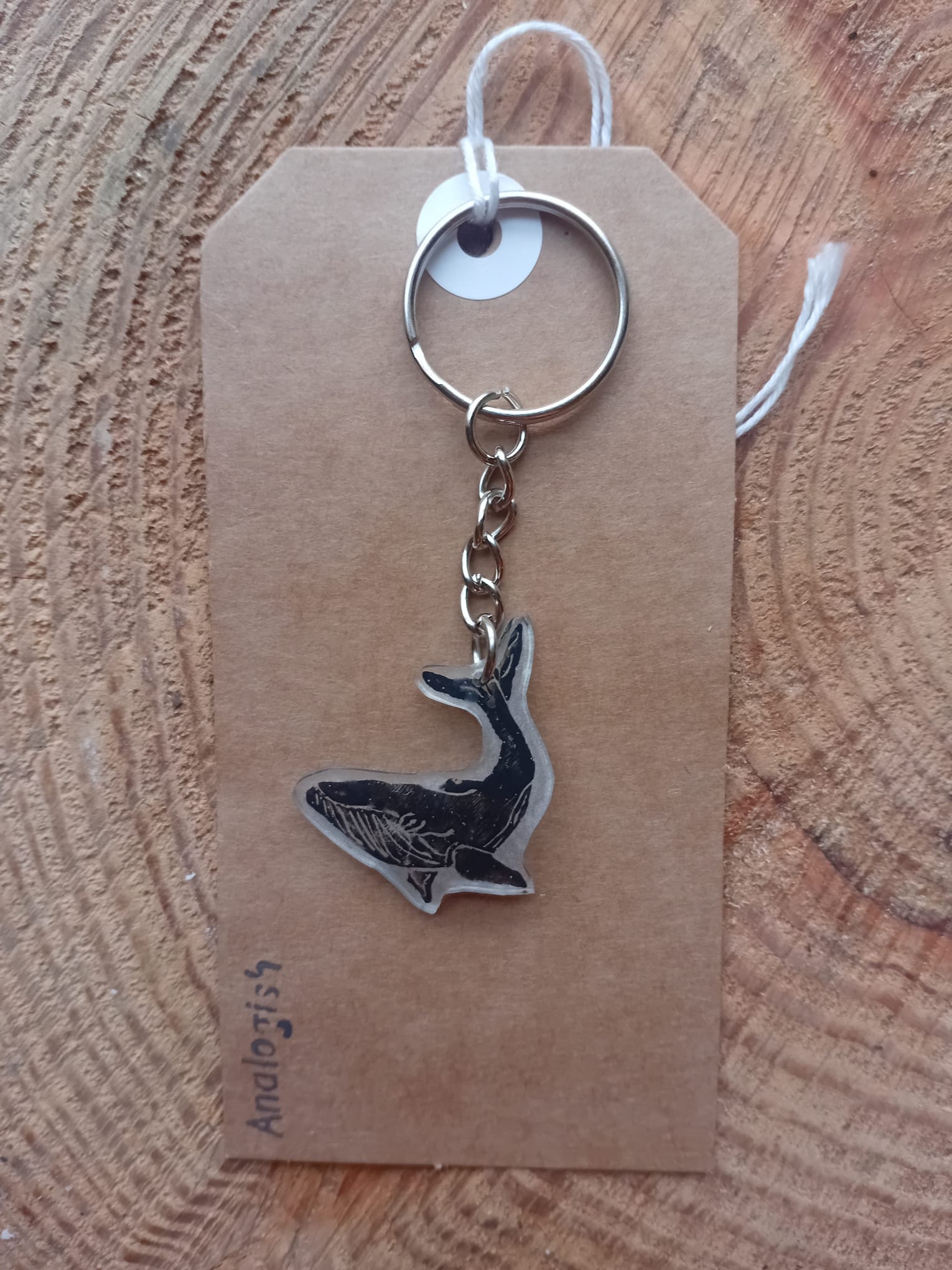 Keychain with whale design on a brown tag against a wooden background