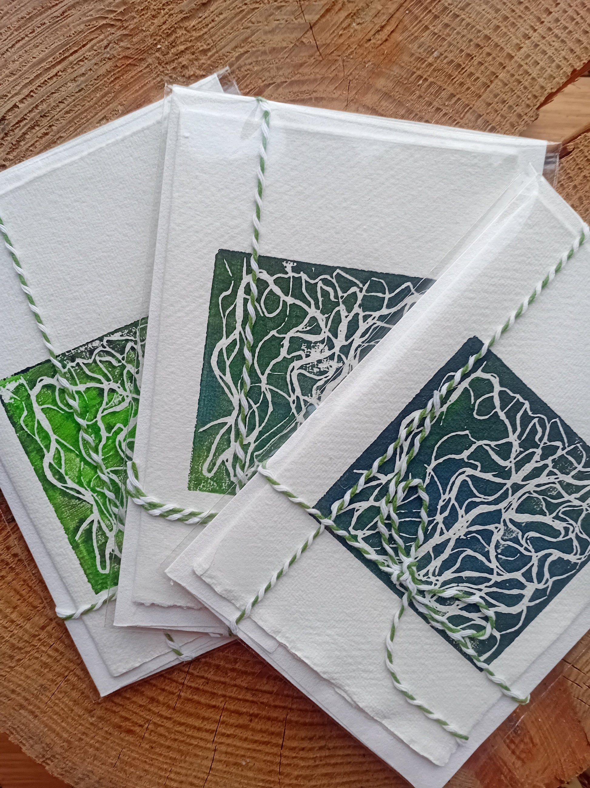 A trio of Analogish lino printed cards on a wooden surface.