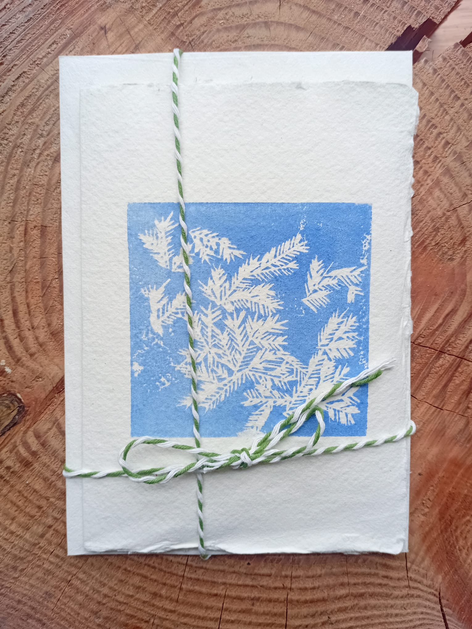 Original lino print card made with handmade paper depicting hoar frost on a wooden background. 