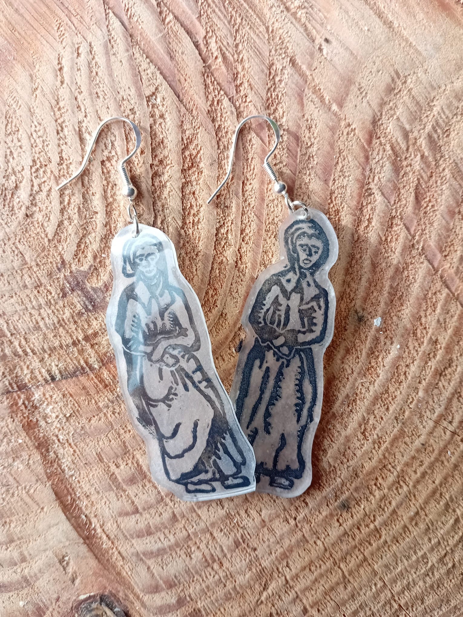 Pair of earrings with a design on a wooden surface. These earrings have been made from an original lino cut. 